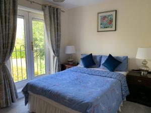 Schlafzimmer mit einem Bett mit blauer Bettwäsche und einem Fenster in der Unterkunft Two Bedroom Town House Beside The River Barrow in Carlow