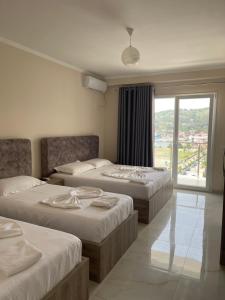 a hotel room with three beds and a window at Hotel Fredi Shengjin in Shëngjin