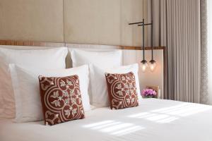 a bedroom with a bed with white sheets and pillows at The Norman Tel Aviv in Tel Aviv
