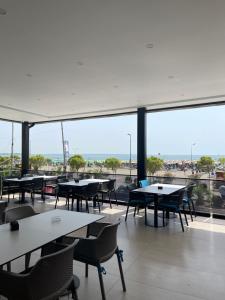 a cafeteria with tables and chairs and a large window at Hotel Fredi Shengjin in Shëngjin