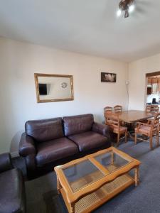 ein Wohnzimmer mit einem Ledersofa und einem Tisch in der Unterkunft Carnarvon Street City Centre Apartment in Glasgow