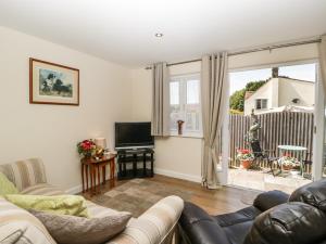 a living room with a couch and a television at Glebe Lodge in Westbury-sub-Mendip