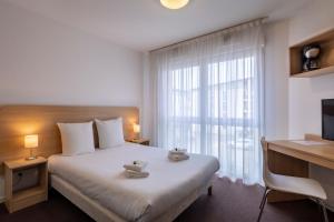 a bedroom with a bed and a desk and a window at The Originals Residence, Kosy Appart'hotels Troyes City & Park in Troyes +20 photos