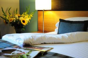 ein Hotelzimmer mit einem Bett mit einer Blumenvase in der Unterkunft Craigmhor Lodge & Courtyard in Pitlochry