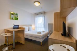 Cette chambre comprend un lit et un bureau avec un ordinateur portable. dans l'établissement The Originals Residence, Kosy Appart'hotels Troyes City & Park, à Troyes