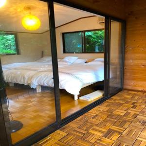 a bedroom with two beds and a glass wall at THE HIGHEST VILLA IZUMI - Vacation STAY 07935v in Nakatsugawa