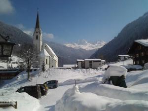 a church covered in snow with cars parked in it at Haus Ruepp in Silbertal