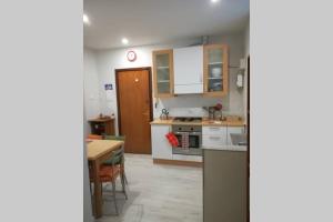 una cocina con armarios blancos y una mesa en una habitación en Casa Vacanze La CartolinA, en Trieste