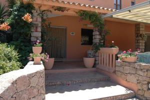 ein Haus mit Blumentöpfen auf der Veranda in der Unterkunft Hotel Mediterraneo in Costa Paradiso
