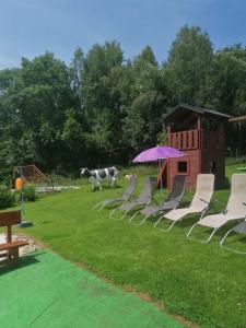 eine Gruppe Stühle und ein Regenschirm auf einem Hof in der Unterkunft Apartments Iwona in Rokytnice nad Jizerou