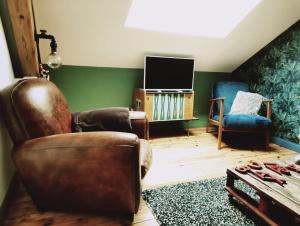 a living room with a leather chair and a tv at Le Chic Broc Ground in Vichy