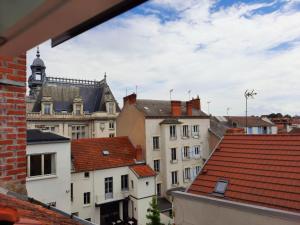 a view of roofs of buildings with a clock tower at Le Chic Broc Ground in Vichy