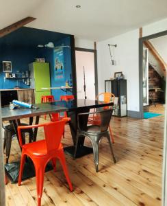 a dining room with a black table and orange chairs at Le Chic Broc Ground in Vichy