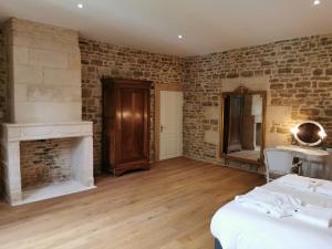 Una habitación con paredes de ladrillo y una cama y una chimenea. en La Maison des mariés - Nature & Sèvre Niortaise, en Sciecq