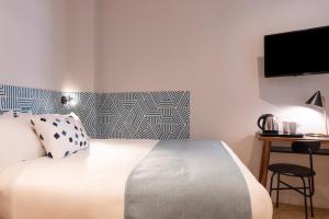 um quarto com uma cama e uma secretária com uma televisão em Paris Art Hotel Quartier Latin by Malone em Paris