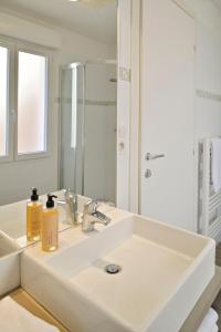 ein weißes Badezimmer mit Waschbecken und Spiegel in der Unterkunft Residence Des Îles in LʼÎle-Rousse