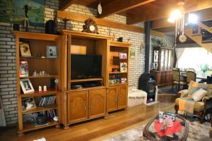 una sala de estar con TV en un centro de entretenimiento de madera en Sítio Dos Amigos en Canela