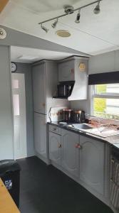 uma cozinha com armários cinzentos e um forno com placa de fogão em 4 Squirrel View em Stranraer
