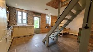 a kitchen with a staircase in the middle of a room at La Belle Petite Ferme Rosiers de Julliac 19350 in Les Bos
