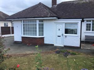 ein weißes Haus mit einer weißen Tür und einem Hof in der Unterkunft 3 bed bungalow Penrhyn Bay Llandudno in Llandrillo-yn-Rhôs