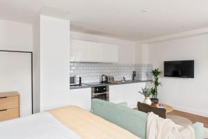 a white bedroom with a bed and a kitchen at Cove Minshull Street in Manchester