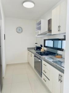 uma cozinha com armários brancos e um forno com placa de fogão em Apartamento Cleo em Cancún