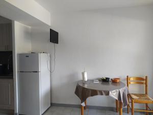 a kitchen with a table and a white refrigerator at charmant studio à Balaruc les bains in Balaruc-les-Bains