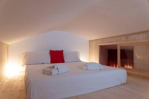 a bedroom with a large white bed with a red pillow at enJoy Home - Mansarda Piccolo Tesoro in Padova