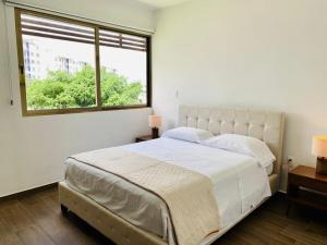 a white bedroom with a large bed and a window at Apartamento Cleo in Cancún
