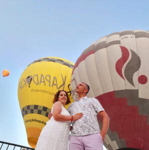 a bride and groom standing in front of hot air balloons at Cappadocia Fairy Tale Suites in Çavuşin