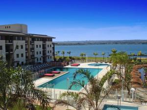 a resort swimming pool with a view of the water at Flat no Life Resort a Beira Lago in Brasília