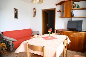uma sala de estar com uma mesa e um sofá vermelho em Apartma Čuk em Dutovlje