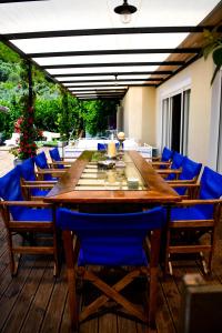 uma grande mesa de madeira com cadeiras azuis num deque em Serenity Luxury Villa, Skiathos em Agia Paraskevi