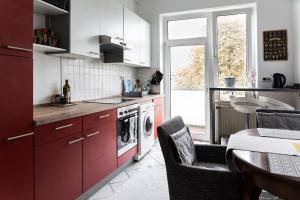 a kitchen with red cabinets and a washing machine at Beautiful Cozy 1-Room apartment, near Rhine in Düsseldorf
