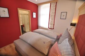 1 dormitorio con paredes rojas y 1 cama con almohadas en Wohlfühl-Ferienwohnungen König, en Bad Elster
