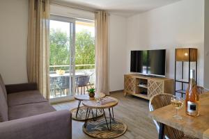 ein Wohnzimmer mit einem Sofa und einem TV in der Unterkunft Residence Des Îles in LʼÎle-Rousse