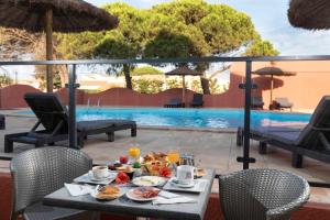 a table with food on it next to a pool at The Originals City, Relax'Otel & Spa, Le Barcarès in Le Barcarès