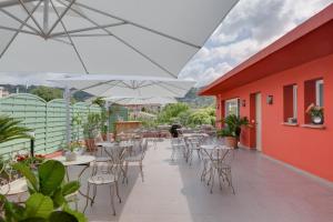 un patio al aire libre con mesas, sillas y sombrillas en Hôtel CasaBella, en Mouans-Sartoux