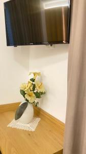 un jarrón con flores en una mesa bajo una TV en Villa Vera, en Ora - Auer