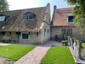 a brick house with a brick walkway in the yard at Kakebiën in Hollum