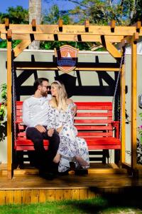 a man and a woman sitting on a red bench at Chalé Suiço Bombinhas in Bombinhas +72 photos