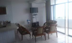 a living room with three chairs and a table and a room with windows at Casa blanca Atacames in Atacames