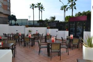 a patio with tables and chairs and palm trees at Gran Hotel Toledo in Onda