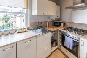 a kitchen with white cabinets and a stove top oven at 10 Grove St - Bath Holiday Suites in Bath