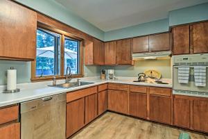 a kitchen with wooden cabinets and a sink and a window at Lake Huron House with Grill and Beach Access! in East Tawas