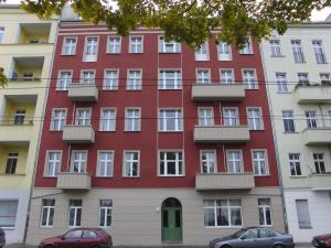 un bâtiment rouge avec balcon et voitures garées devant lui dans l'établissement Nice studio in Friedrichschain area, à Berlin