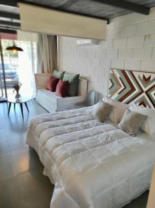 1 dormitorio con 1 cama blanca grande y 1 sofá en Apart Las Tunas Carmelo, en Carmelo