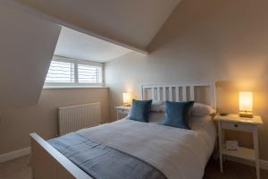 a bedroom with a bed with blue pillows and a window at Stowaways Loft in Whitby