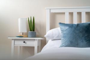a white bed with a blue pillow and a table with a plant at Stowaways Loft in Whitby +19 photos