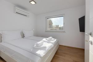 a white bedroom with a bed with a window at Apartma Skubic Duhljica in Vantačići +39 photos